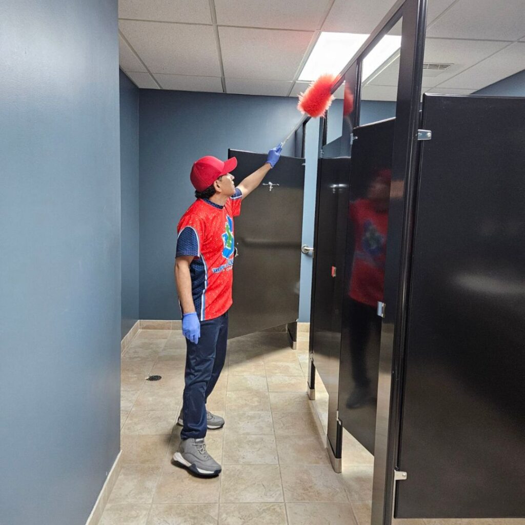 Commercial restroom cleaning in Omaha – Triple J Cleaning team member dusting high areas for a spotless business facility